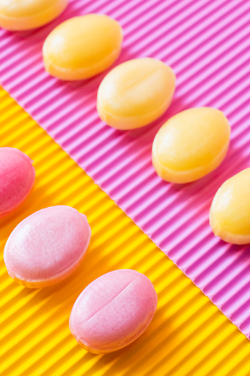 Flat lay with sweet candies on textured pink and yellow background