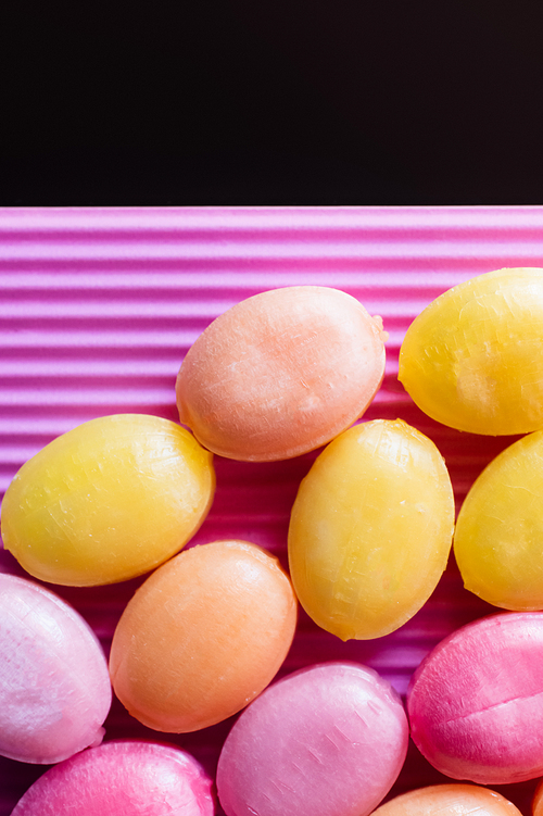 Close up view of candies on textured pink isolated on black