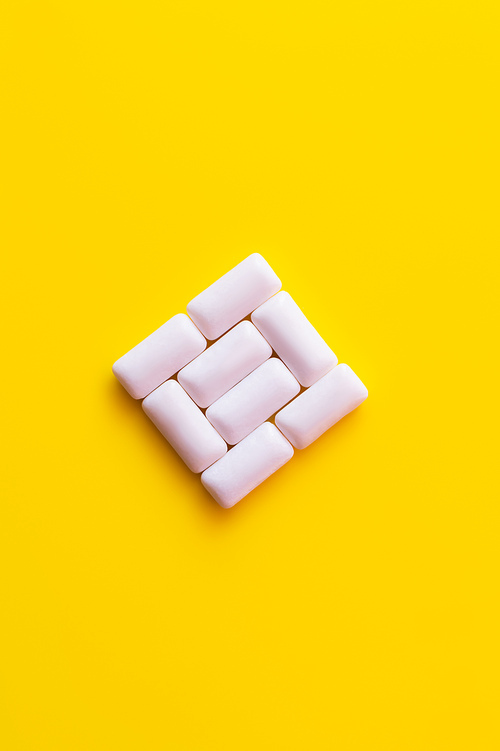 Flat lay of chewing gums in square shape on yellow background