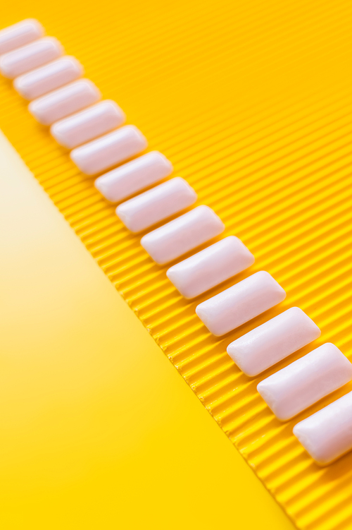 Flat lay from white chewing gums on yellow background with copy space