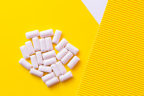 Top view of white chewing gums on yellow background