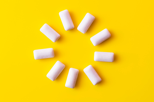 Flat lay of round shape from chewing gums on yellow background