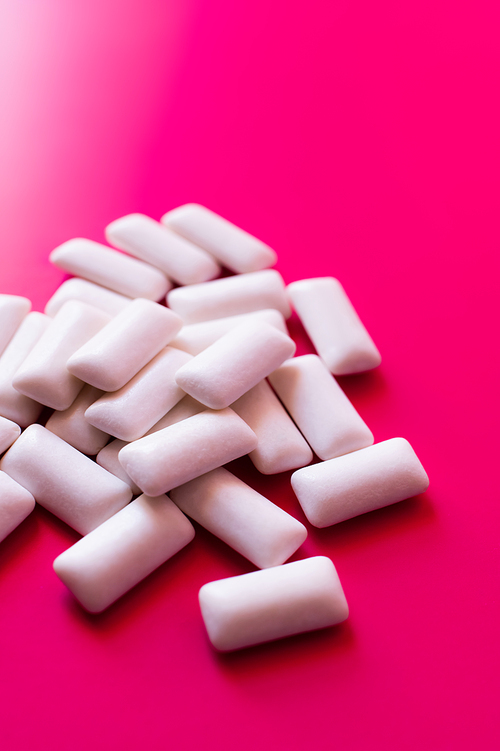 Close up view of white chewing gums on pink background