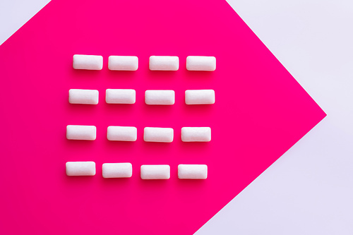 Flat lay with chewing gums on pink and white background