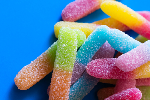 Close up view of gummy sweets with sugar on blue background