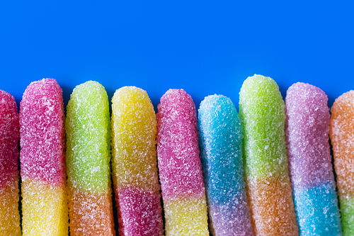 Close up view of gummy sweets with sugar on blue background