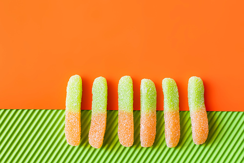 Top view of jelly sweets on orange and green surface