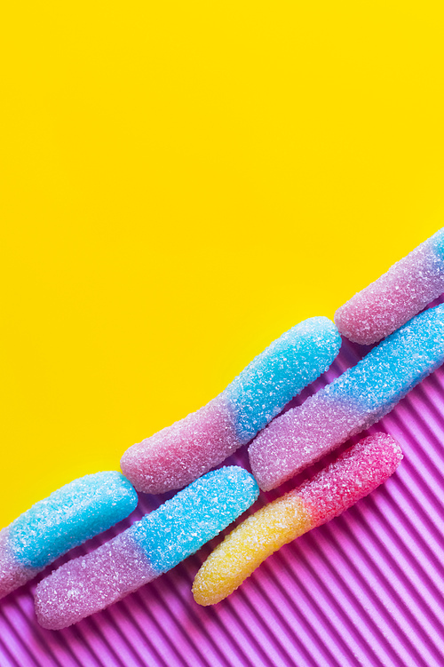 Flat lay of colorful gummy sweets on pink and yellow background