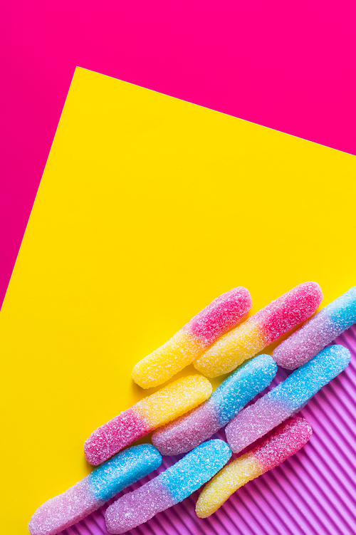 Flat lay with jelly sweets with sugar on pink and yellow background