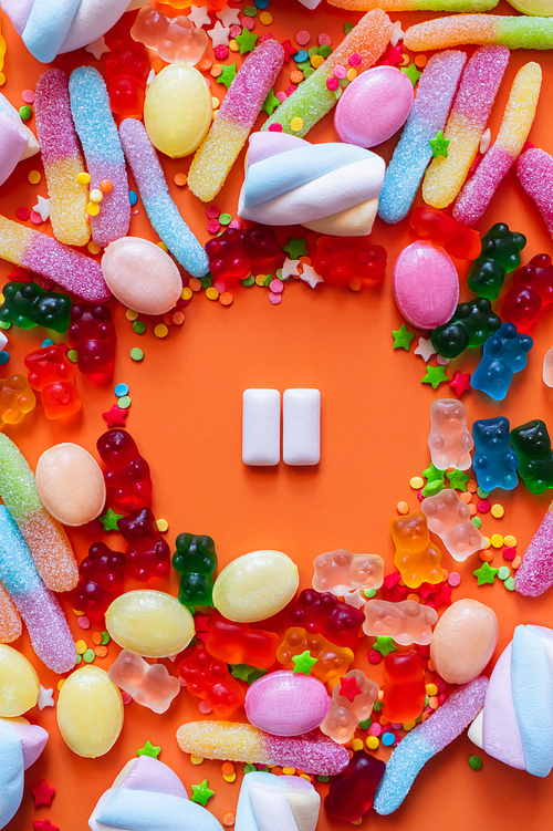 Flat lay with chewing gums near jelly sweets and candies on orange background