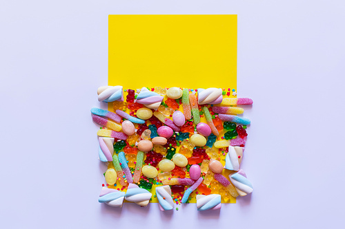Top view of sweet candies and marshmallows on white and yellow surface