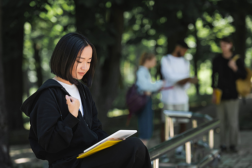 Asian student using digital tablet in park
