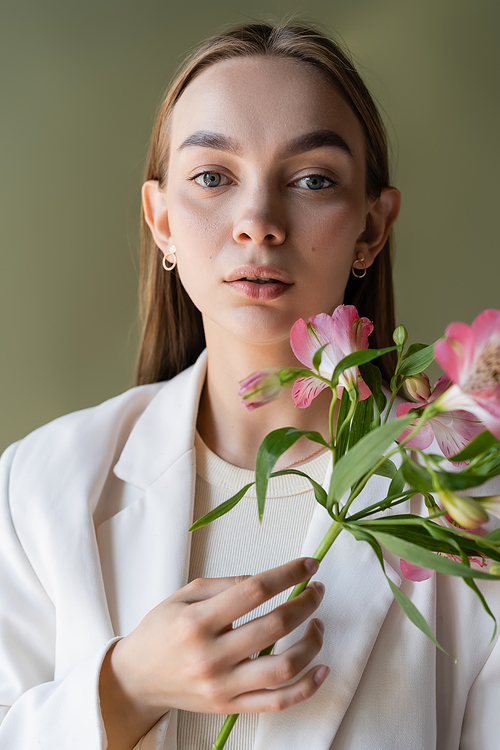 portrait of pretty woman with branch of pink alstroemeria isolated on green