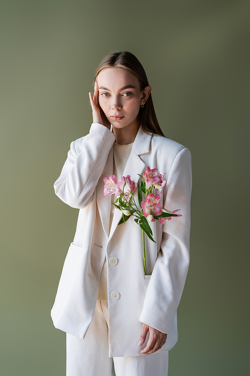 trendy woman with fresh alstroemeria flowers touching face isolated on green