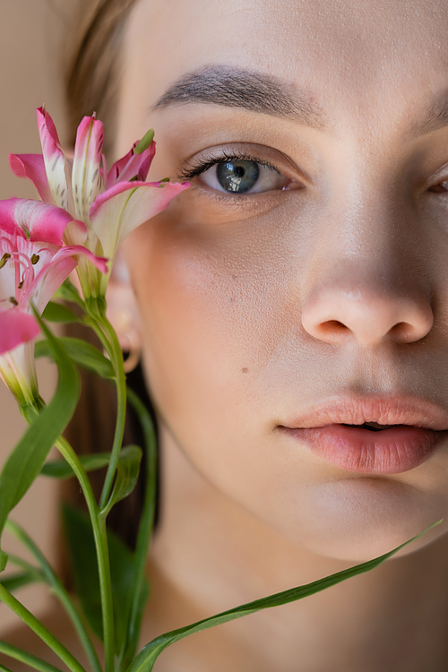 close up portrait of cropped woman with perfect skin near pink alstroemeria flowers