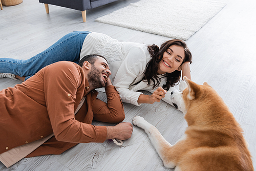 young couple laughing and lying of floor with akita inu dog