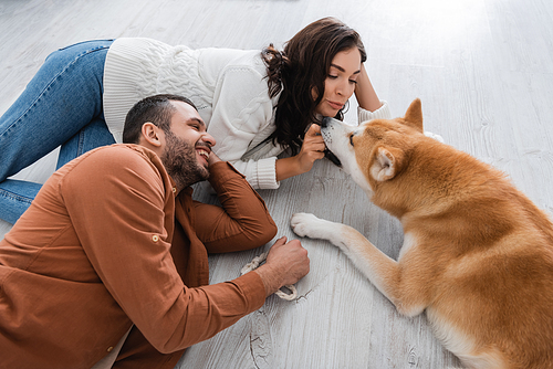 young woman and happy man lying of floor with akita inu dog