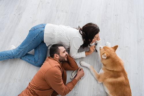 top view of happy young couple lying of floor with akita inu dog