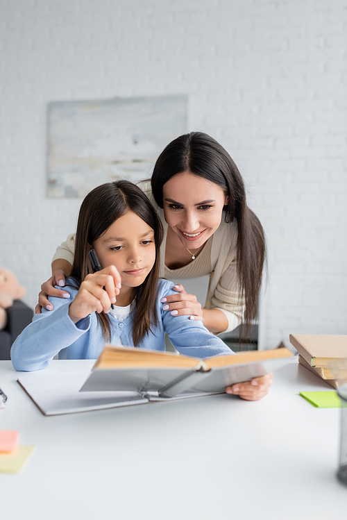 cheerful nanny and child looking at textbook together