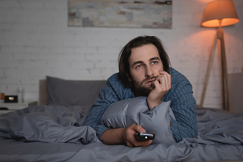 Man with sleep disorder watching movie on bed at night
