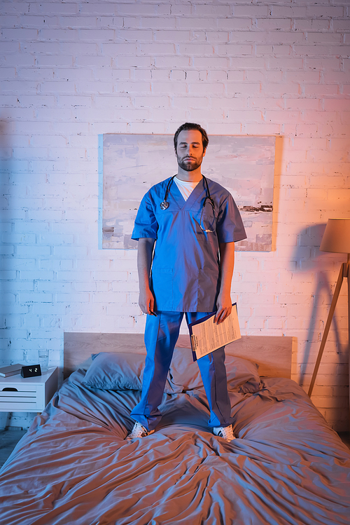 Sleepwalker in doctor uniform holding clipboard while standing on bed at home