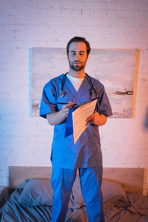 Somnambulist in doctor uniform holding pen and clipboard on bed at night