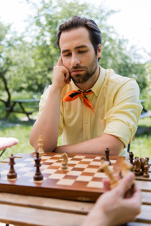 Thoughtful man looking at chess board near girlfriend in park