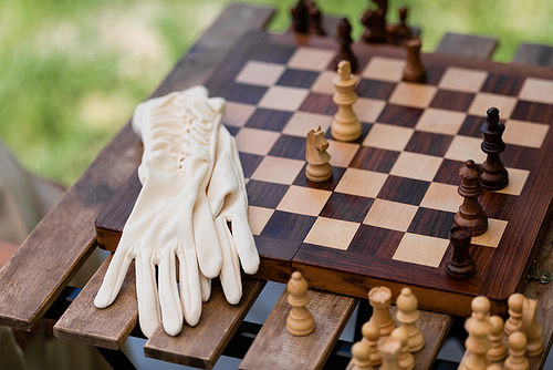 Gloves near wooden figures on chess board in park