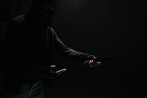 Silhouette of african american robber holding knife isolated on black