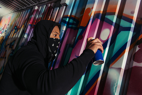 Side view of african american vandal drawing graffiti on wall