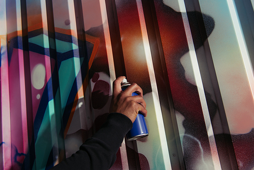 Cropped view of african american vandal drawing graffiti on wall on urban street