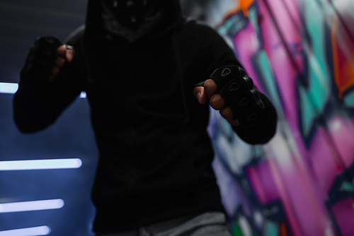 Cropped view of african american hooligan in gloves standing in fighting pose in garage