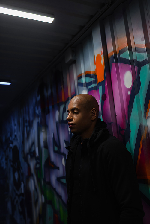 African american hooligan standing near graffiti in garage