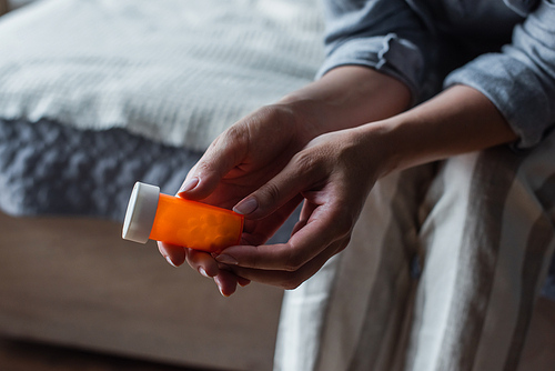 cropped view of woman with menopause holding bottle with pills in hands