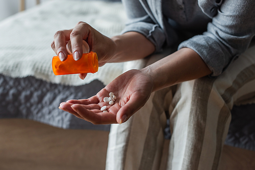 cropped view of woman with menopause holding bottle and pouring pills in hand