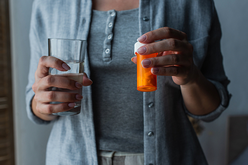 cropped view woman with menopause holding glass of water and medication