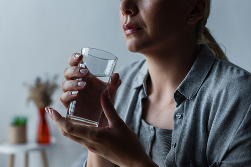 cropped view of sad woman with climax holding glass of water