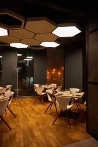 glasses and plates on wooden tables in modern restaurant