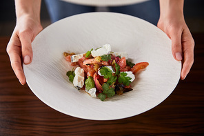 cropped view of woman served delicious restaurant salad with cheese on wooden table