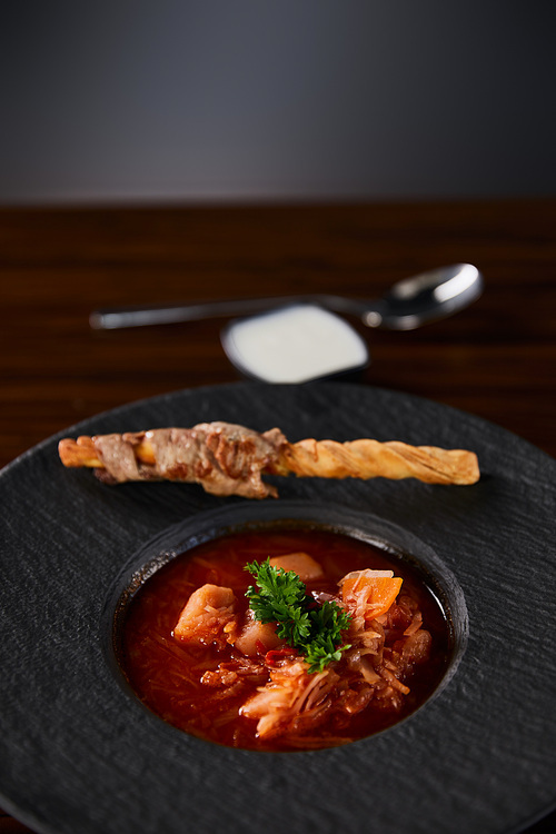 traditional ukrainian borscht garnished with parsley in black plate