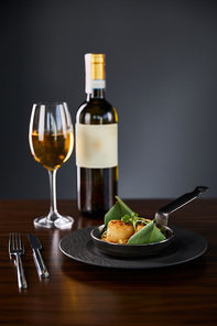 delicious grilled scallops served with cutlery and white wine on wooden table