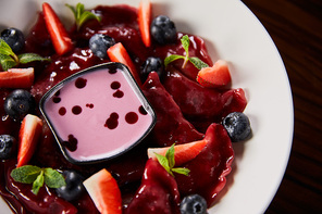 close up view of traditional Ukrainian varenyky with berries served in white plate with sauce