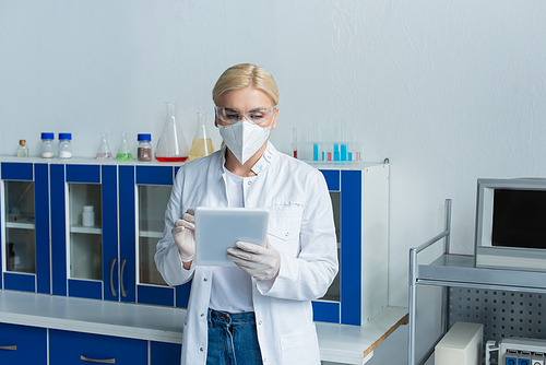 Scientist in protective mask using digital tablet in lab