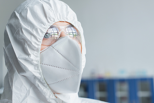 Portrait of scientist in hazmat suit and protective mask looking away in laboratory