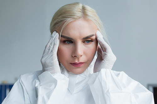 Scientist in protective suit suffering from headache in lab