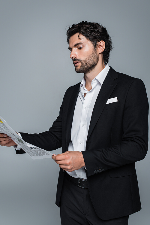 businessman in black blazer and white shirt reading newspaper isolated on grey