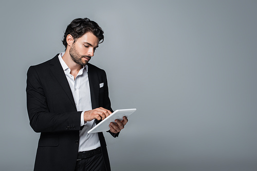 businessman in black blazer and white shirt using digital tablet isolated on grey