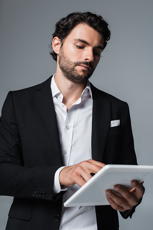 businessman in black blazer and white shirt using digital tablet isolated on grey