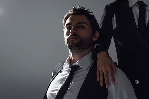 brunette man in white shirt and black tie looking at camera near woman isolated on grey