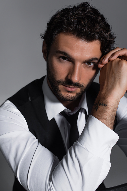 elegant man in white shirt and black tie looking at camera isolated on grey